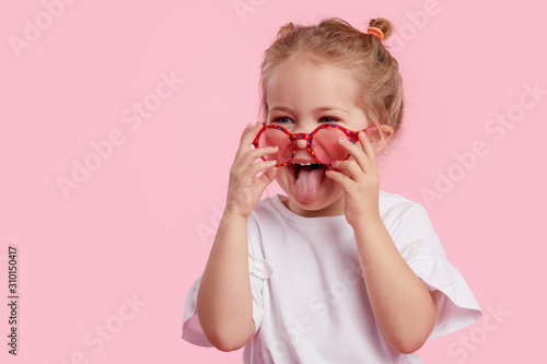 Fototapete Portrait of surprised cute little toddler girl in the heart shape sunglasses