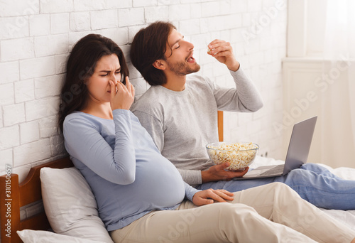 Pregnant woman closing nose, feeling sick with nausea beause of smell photo