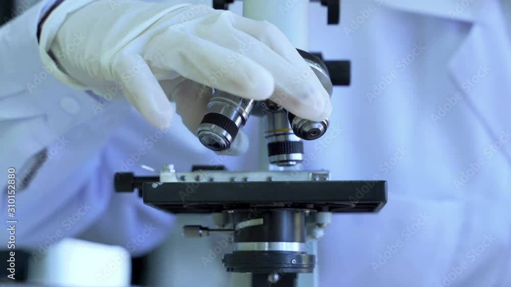 Tilt-up video shot of Medical Research Scientist Looking under the Microscope in the Laboratory. Tilt-up video shot of Medical Research Scientist Looking under the Microscope in the Laboratory.
