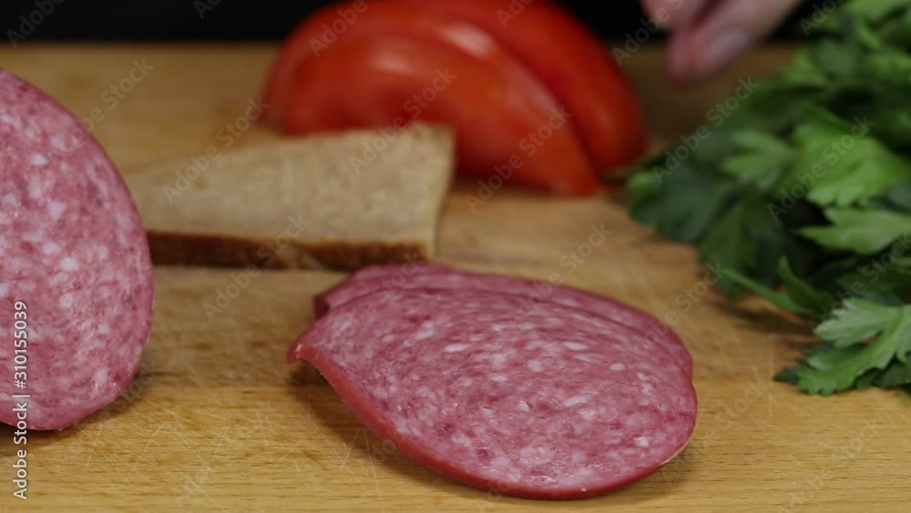 Woman cuts a slice of tomato and puts it on a slice of gray bread, close-up Woman cuts a slice of tomato and puts it on a slice of gray bread, close-up