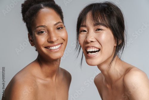 Portrait of two multinational women looking at camera and laughing