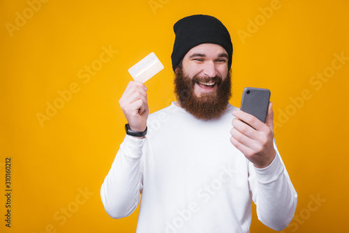 Happy trendy bearded man making online shopping with his new credit card