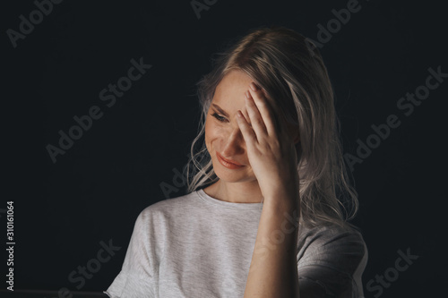 Young model with migraine in the dark studio isolated