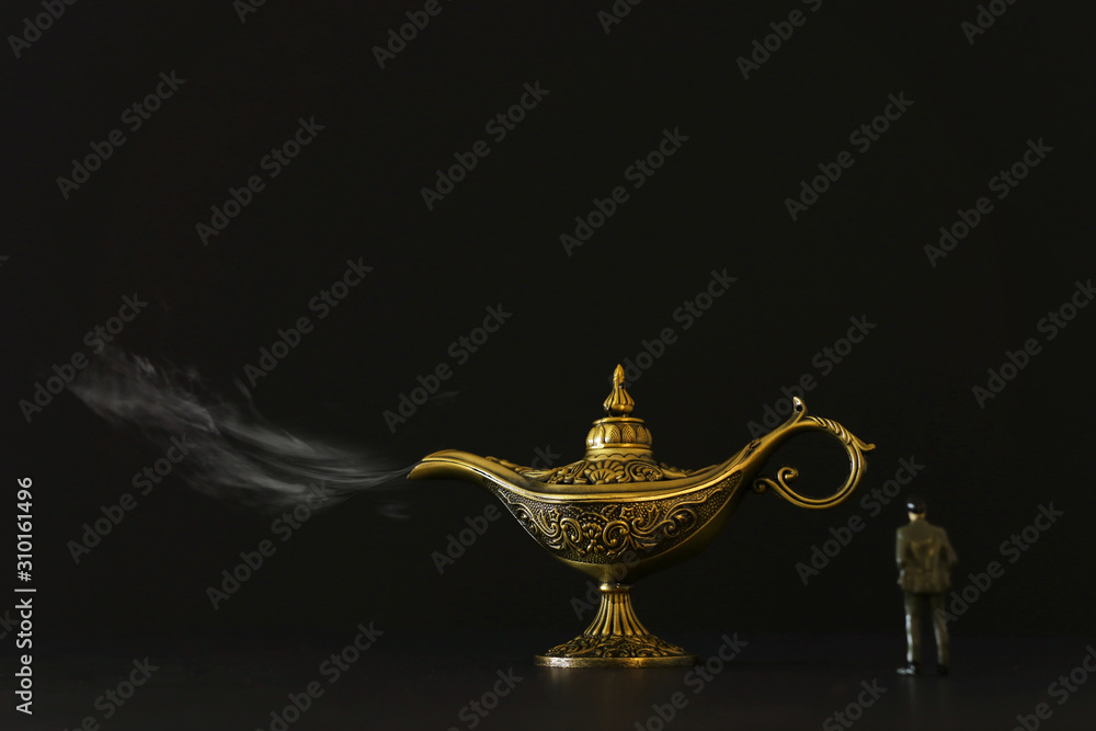 Concept picture of a businessman looking at Aladdin lamp with smoke, asking for a wish Concept picture of a businessman looking at Aladdin lamp with smoke, asking for a wish