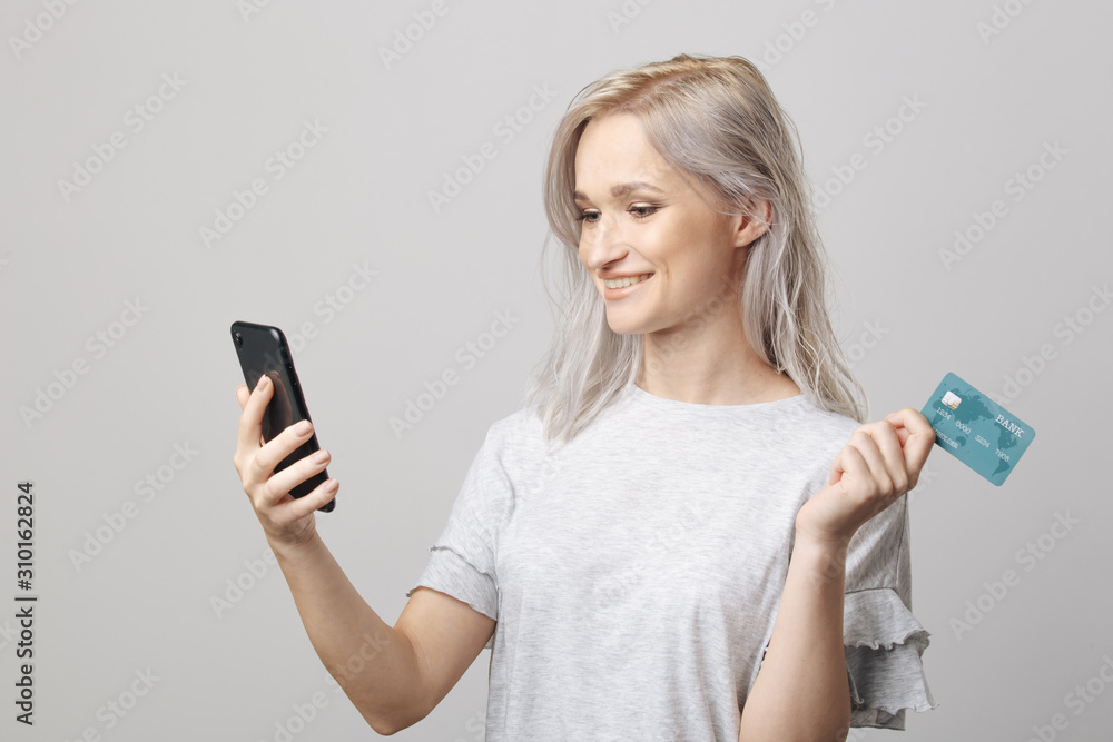 Happy cheerful woman with credit card and phone in the white studio Happy cheerful woman with credit card and phone in the white studio