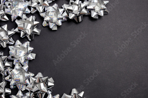 Silver bows on black table top view. Flat lay composition for wedding, christmas or birthday
