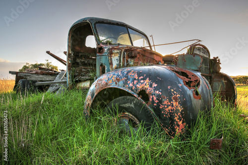 Decaying abandoned old truck overgrown with grass in a field in South Gippsland, Victoria, Australia. photo