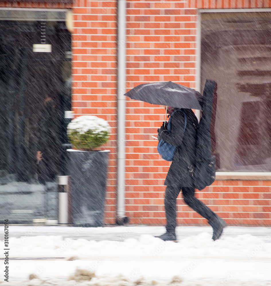 Man with umbrella walking down the street in winter day