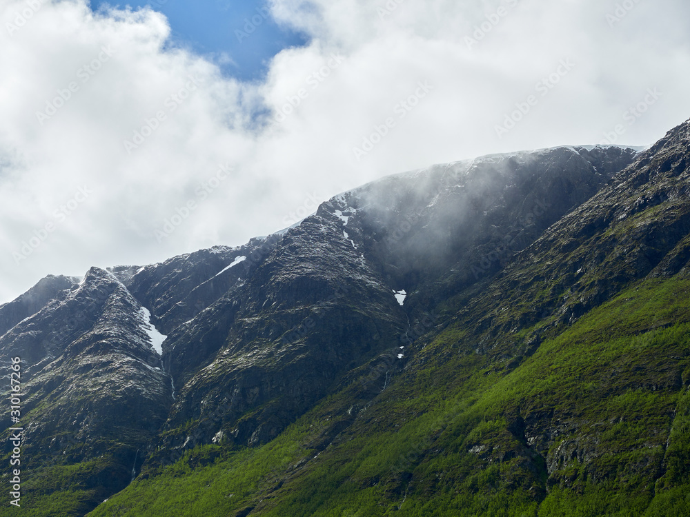 Closeup on snow covered fjords of Norway with ice and snow on the steep mountain edges. Clouds hanging low on the mountain peaks. Closeup on snow covered fjords of Norway with ice and snow on the steep mountain edges. Clouds hanging low on the mountain peaks.