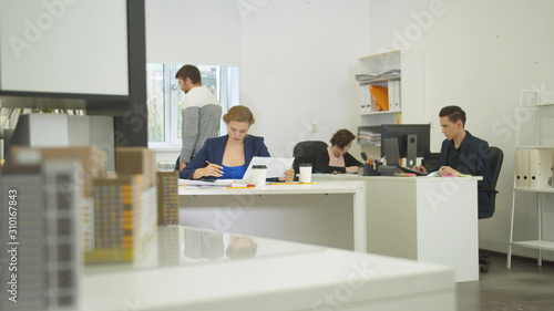 Engineers sit at a tables and work with drawings of apartement