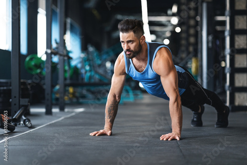 Muscular athlete training on floor at gym