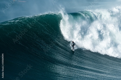 Photography Surfer riding forward the moving foamy wave of the Atlantic Ocean at Nazare, Por
