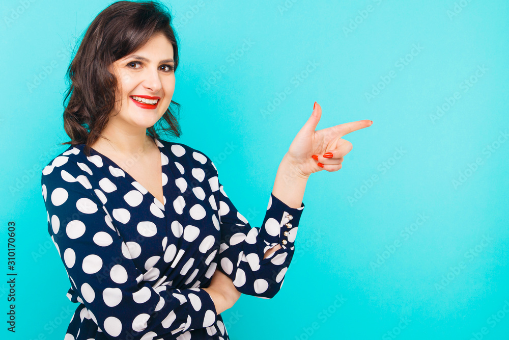 Smiling woman pointing on the blue background Smiling woman pointing on the blue background