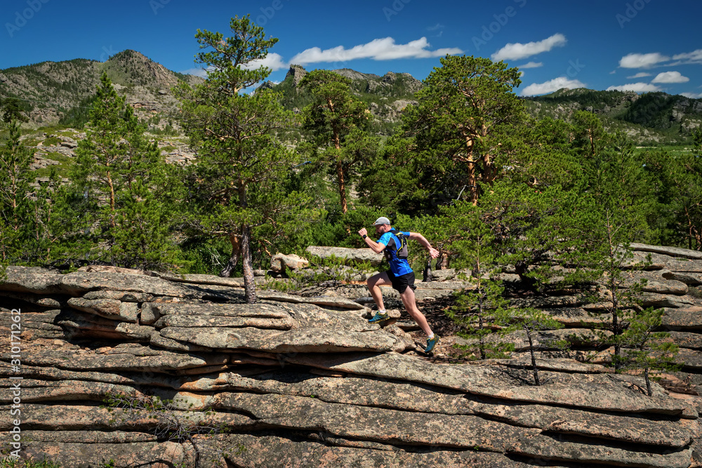 Runner Climbing a Rock. The athlete runs on the rocks in the mountains. Outdoor trail running