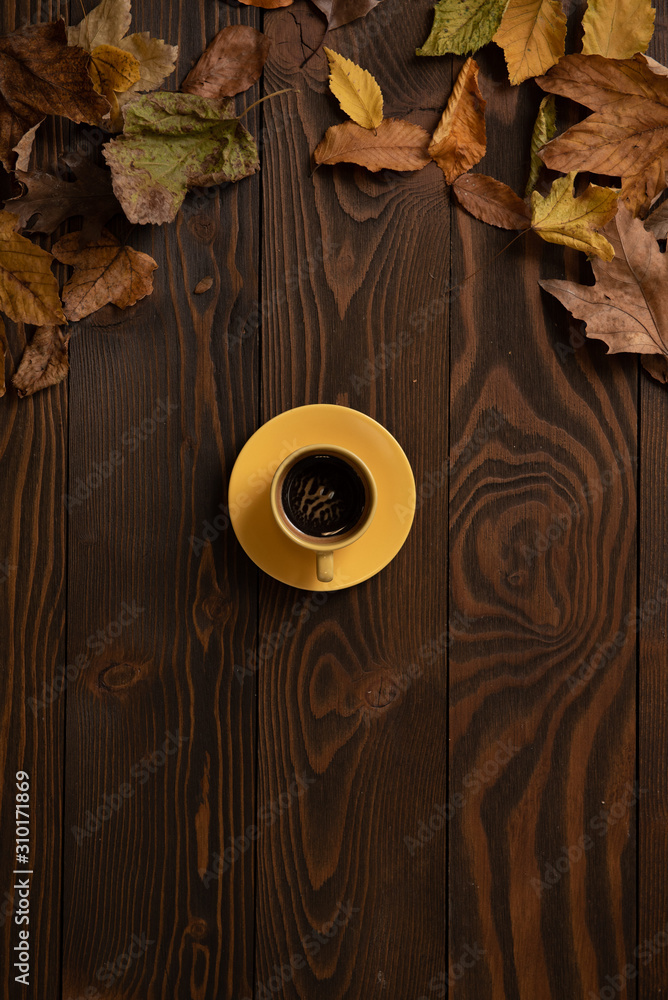 Autumn leaves on a wooden background and a yellow cup of espresso coffee Autumn leaves on a wooden background and a yellow cup of espresso coffee