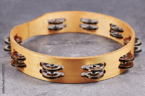 Tambourine percussion music instrument with small metal jingles called 'Zills' on gray background photo