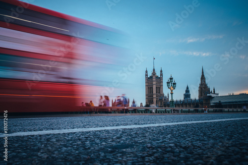 London. Classic red double decker bus crossing Westminster Bridge in front of House of parliament and Big Ben in London.