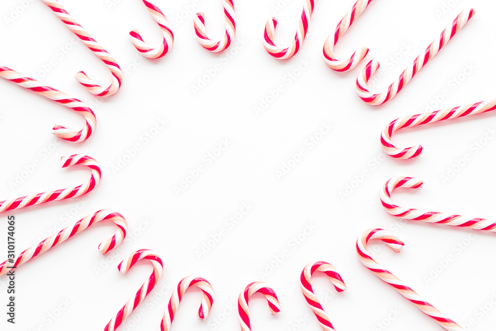 Christmas candies frame - cane with red and white stripes - on white background top-down copy space