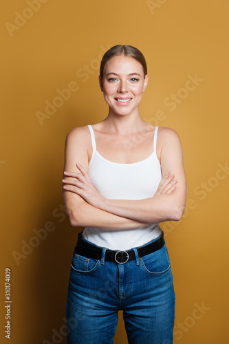 Smiling woman with crossed arms on yellow background © millaf