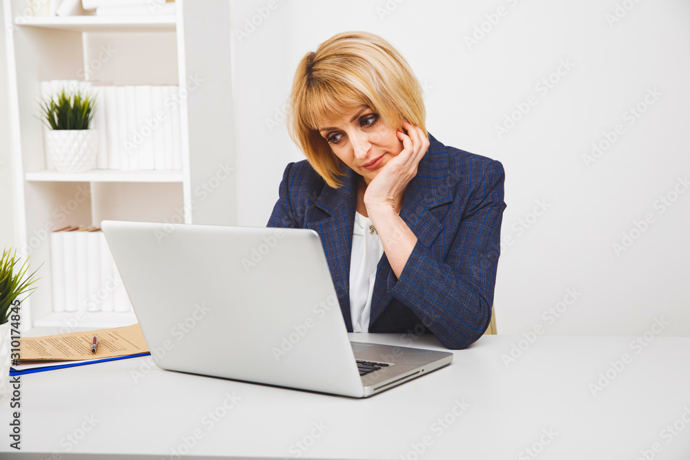 Blond woman sitting at the desk in office and working Blond woman sitting at the desk in office and working