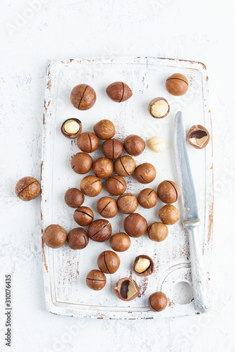 Plate with almonds in endocarp, whole and chopped open nuts in bulk on a cutting board with knife on white background, top view. photo