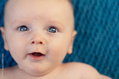 Close up of a baby with bright blue eyes looking at the camera