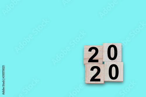 Wood block cube of number 2020 year on blue background.