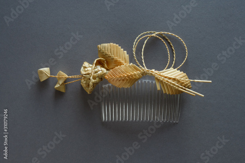 Ornamental hair comb with straw flowers on a gray background