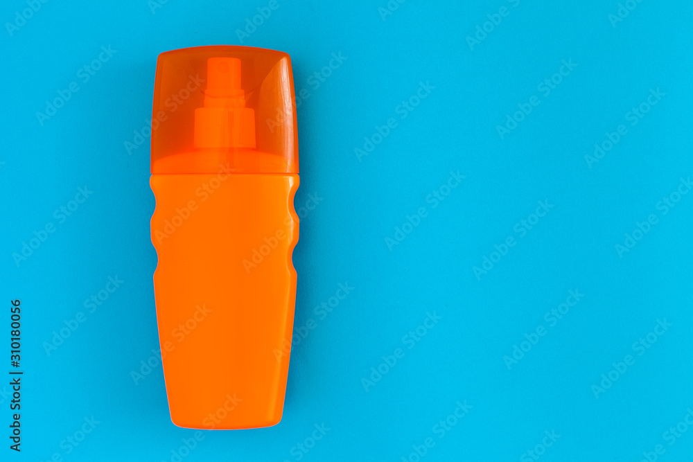 orange bottle with a spray of sunblock for tanning lies on a blue background top view, nobody. orange bottle with a spray of sunblock for tanning lies on a blue background top view, nobody.