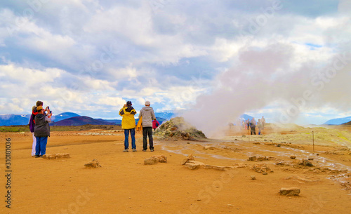 Supernatural landscape at geothermal field Mars like site Hverir Namafjall wasteland with pools of boiling mud, mudpots, hot springs, hissing chimneys of fumaroles and orange and red colors photo