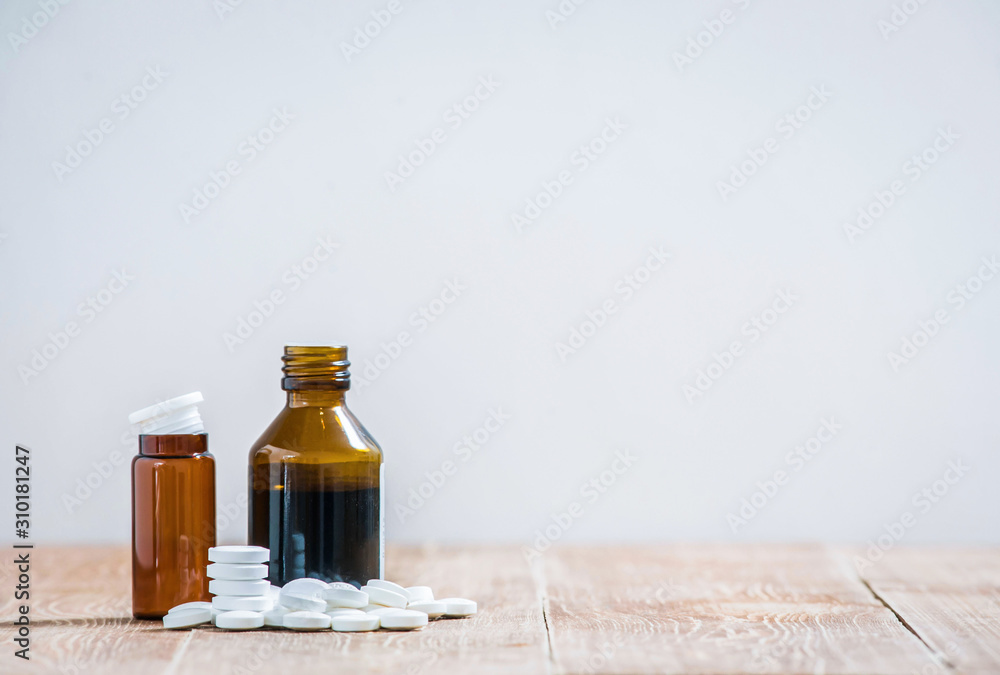 Little medicine bottles and many white tablets on a wooden table. copy space Little medicine bottles and many white tablets on a wooden table. copy space