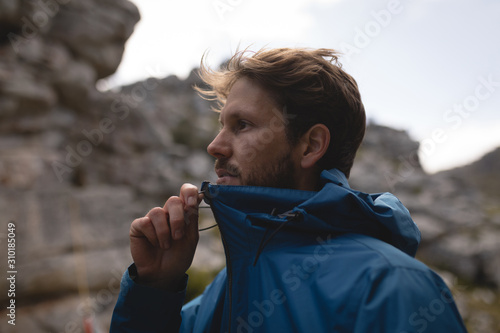 Hiker hand pulling zipper of waterproof rain jacket