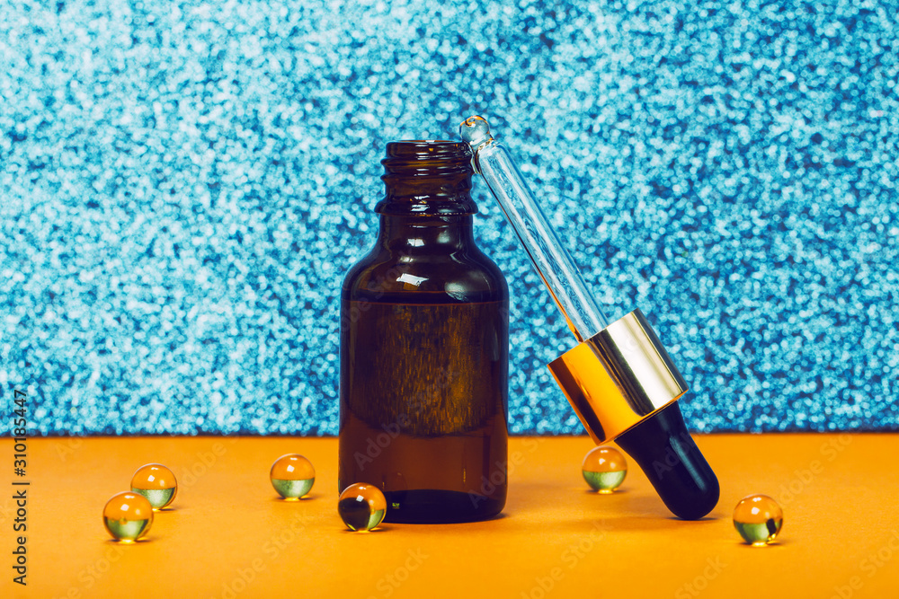Face serum and vitamin capsules on the trendy orange and blue background. Collagen, hyaluronic acid for skin care. Achievements of modern science in cosmetic to preserve beauty. Face serum and vitamin capsules on the trendy orange and blue background. Collagen, hyaluronic acid for skin care. Achievements of modern science in cosmetic to preserve beauty.