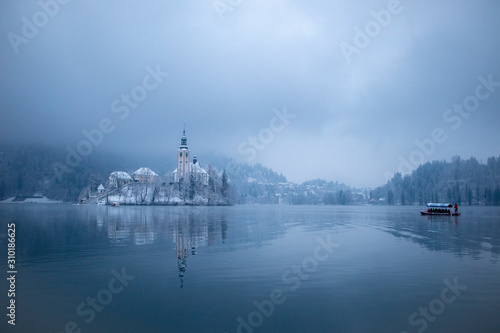 Lake Bled in winter season with snow and tourist boats © LAMushom