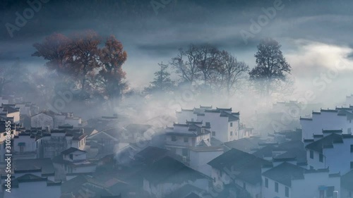 time lapse of beautiful autumn landscape in wuyuan, traditional hui-style buildings and tall maple trees, shicheng village in the morning, jiangxi province ,China photo