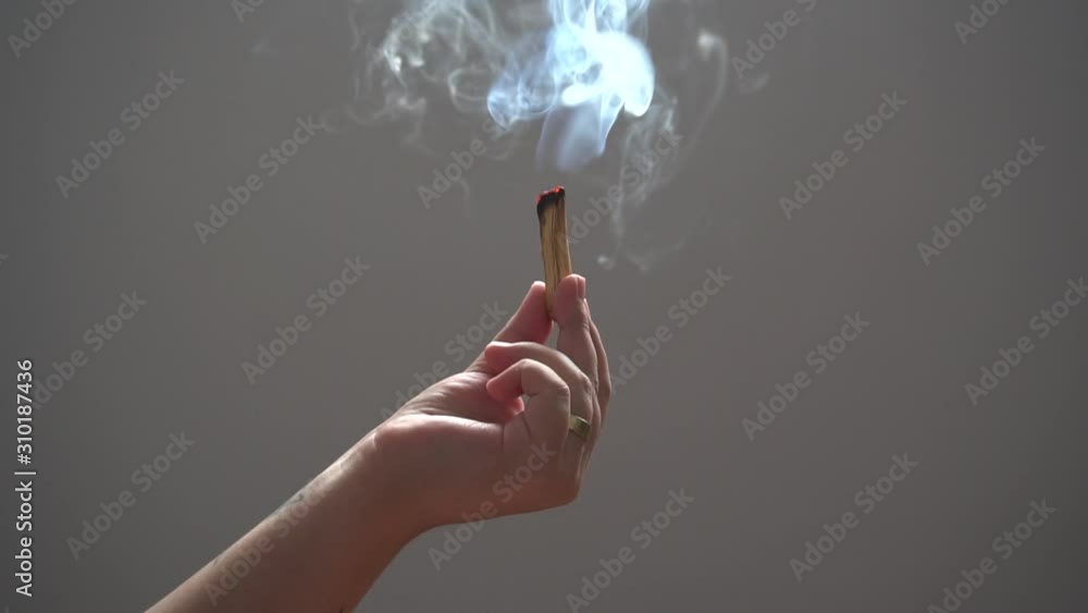mão feminina segurando palo santo queimando
