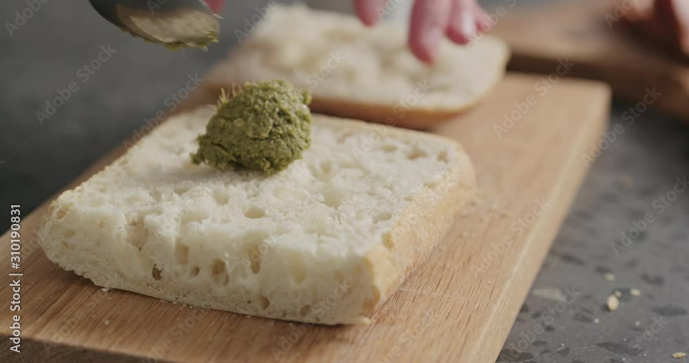 Slow motion man spread pesto on ciabatta slice on oak board Slow motion man spread pesto on ciabatta slice on oak board