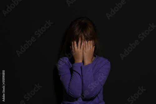 Valokuva Abused little girl crying near black wall