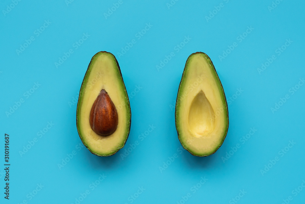 Avocado halves on blue background. Top view. Minimal summer food concept. Flat lay