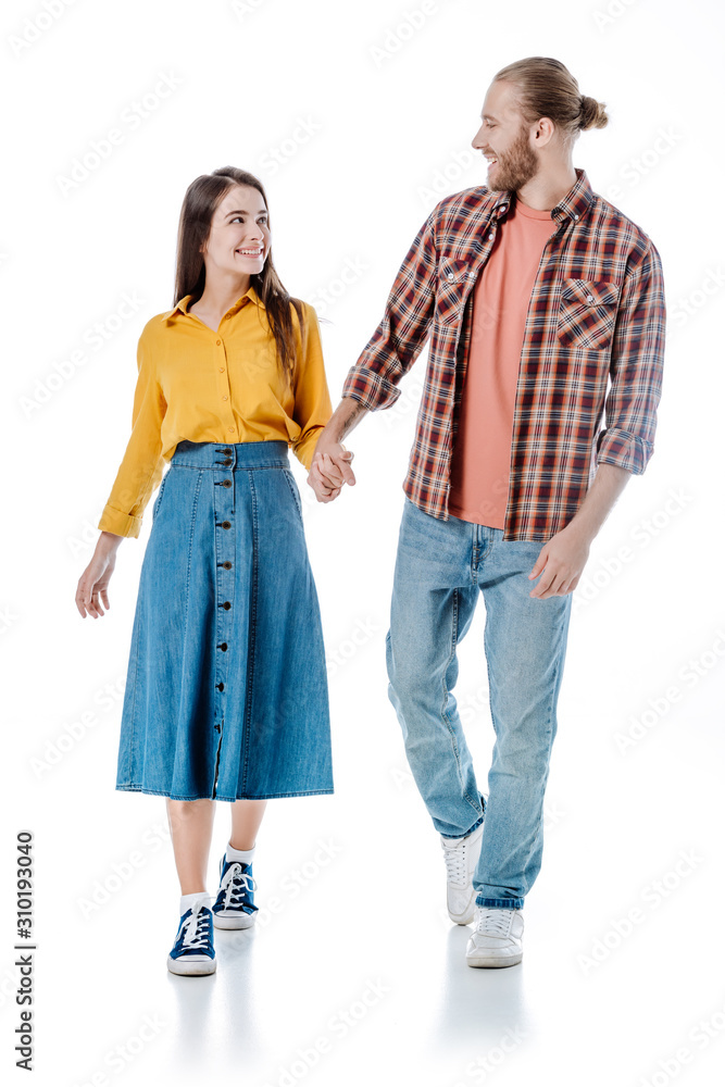full length view of happy young couple in casual outfit walking and holding hands isolated on white full length view of happy young couple in casual outfit walking and holding hands isolated on white