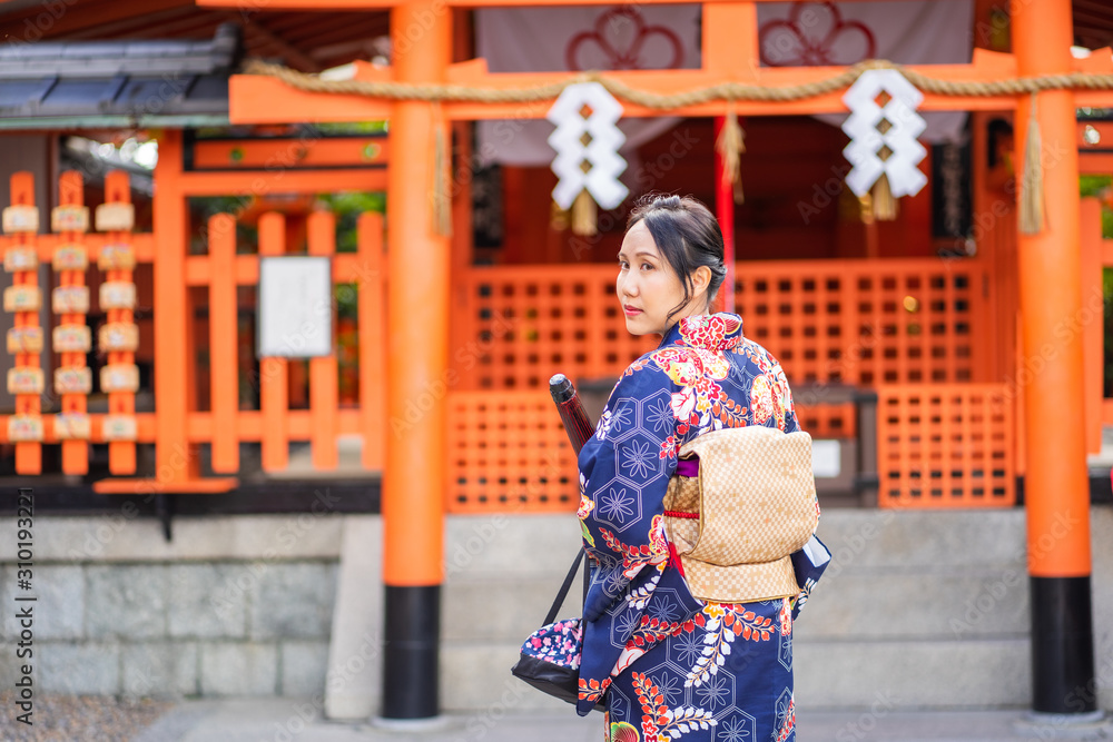 Geishas girl wearing Japanese kimono among red wooden Tori Gate at Fushimi Inari Shrine in Kyoto, Kimono is a Japanese traditional garment. The word Geishas girl wearing Japanese kimono among red wooden Tori Gate at Fushimi Inari Shrine in Kyoto, Kimono is a Japanese traditional garment. The word