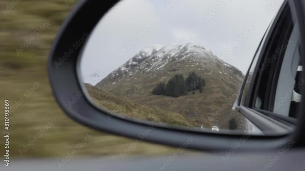 Snowy mountain top in reflection of sideview mirror of car on roadtrip Snowy mountain top in reflection of sideview mirror of car on roadtrip