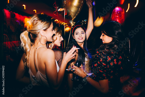 Group of female friends at club drinking wine and having fun. New year party