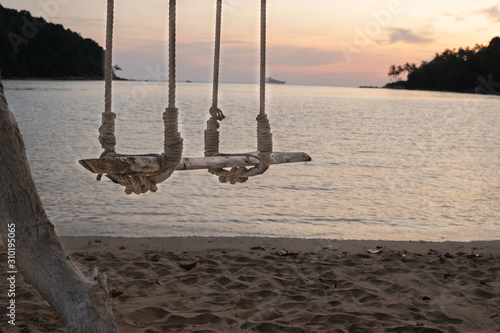 Wooden swing hang under a tree sand and sea beach on the background