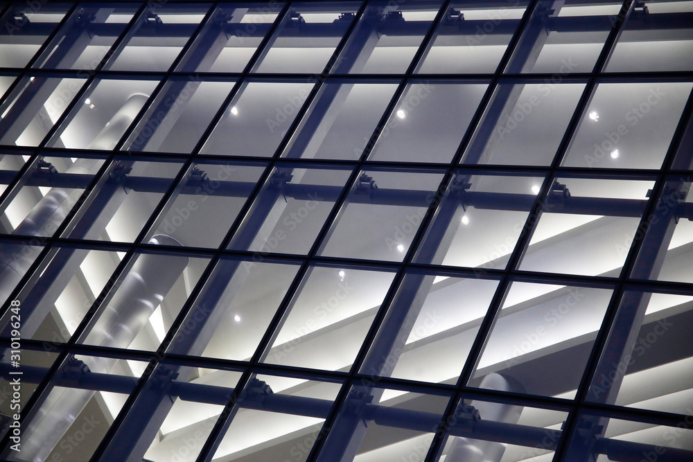 Close-up of structural glazing. Generic modern architecture fragment featuring glass facade wall panels. Abstract urban background. Transparent grid pattern and girders. Geometric polygonal structure. Close-up of structural glazing. Generic modern architecture fragment featuring glass facade wall panels. Abstract urban background. Transparent grid pattern and girders. Geometric polygonal structure.