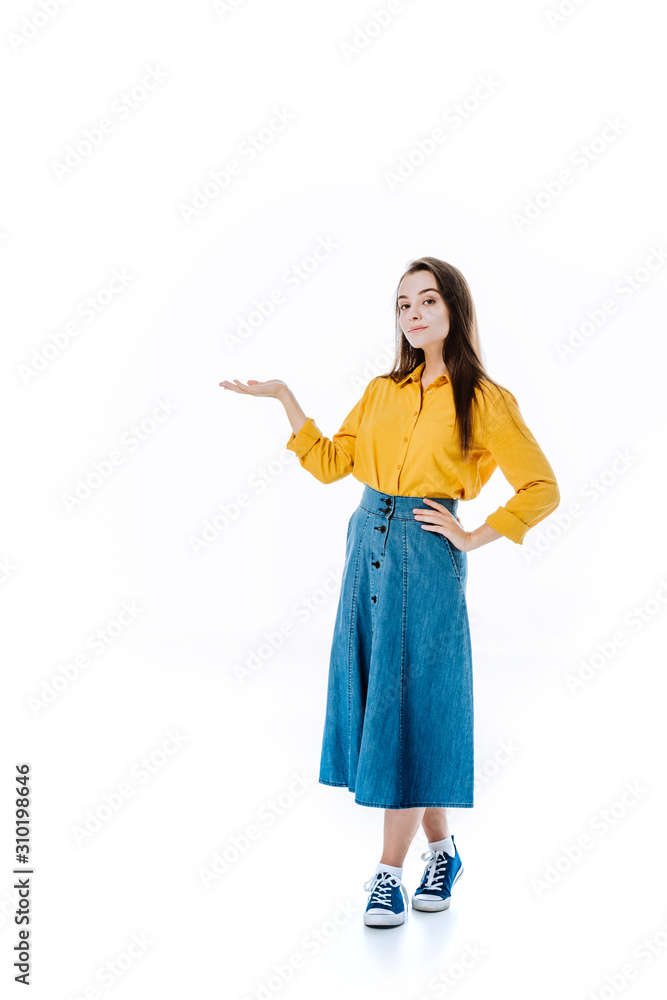 full length view of attractive girl in denim skirt pointing with hand isolated on white full length view of attractive girl in denim skirt pointing with hand isolated on white