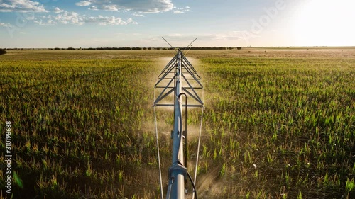 Creative point of view timelapse on top of centre pivot irrigation system at sun set, with cumulous clouds while sprinklers are on to water corn (maize), South Africa.