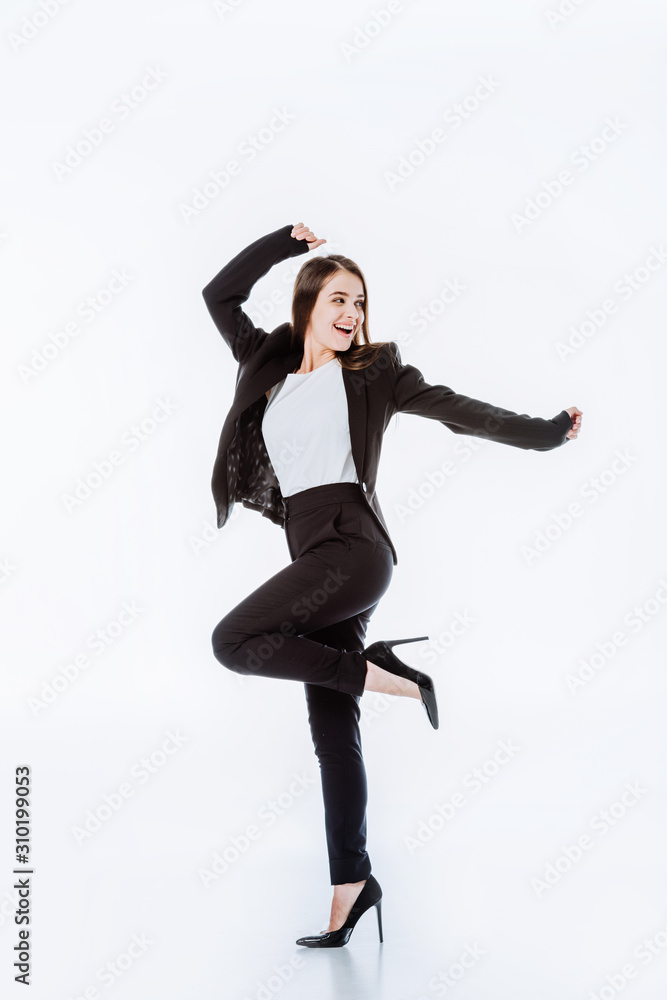 full length view of happy businesswoman in suit posing isolated on white
