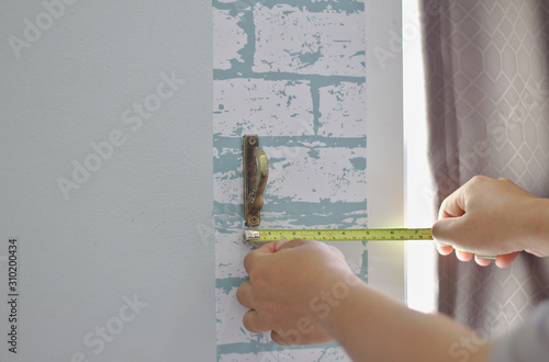 The yellow tape measure measures the distance of the curtain storage installation. From the window sill Sunlight curtains installation. Get curtain installation.Modern curtains in the house with hooks