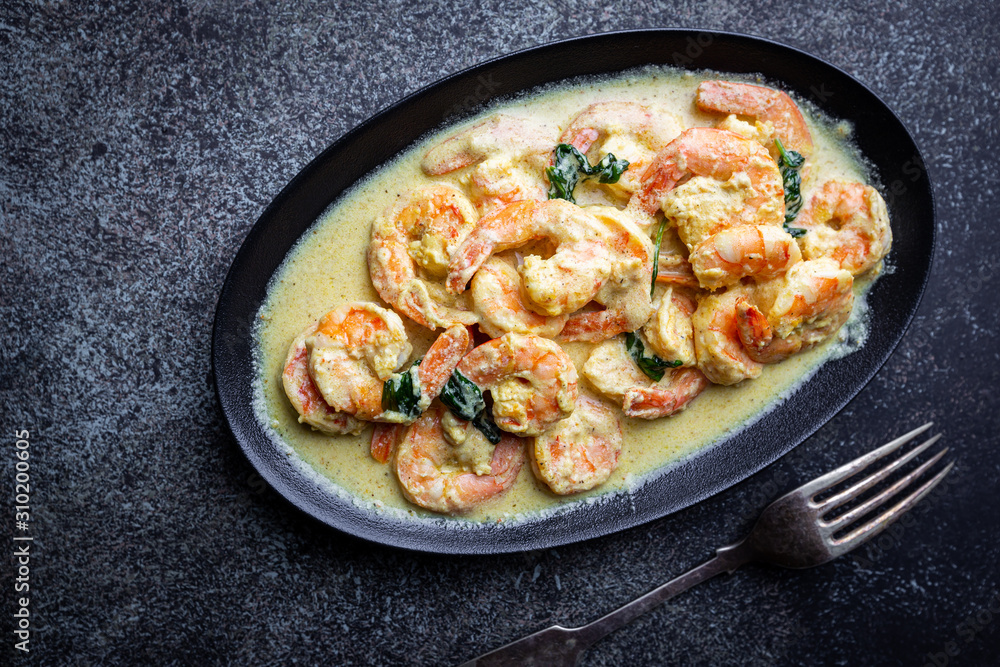 Shrimps in cream sauce with Coconut milk on a plate over black background, top view or view from above, flat lay Shrimps in cream sauce with Coconut milk on a plate over black background, top view or view from above, flat lay
